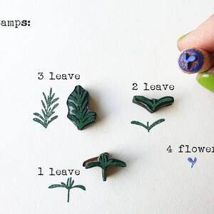 May include: Four stamps for crafting, featuring a blue flower, and three different green leaf designs. The text "4 Stamps" is written at the top of the image.