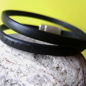 Puede incluir: Pulsera de cuero negro con cierre plateado y la inscripción "la-di-da la-di-da" grabada en la banda.