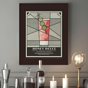 May include: A framed print of a cocktail recipe called "Honey Deuce". The print features a stylized illustration of a cocktail with a green olive garnish in a glass. The recipe is printed below the illustration.