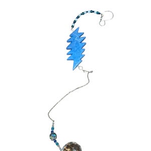 May include: A blue lightning bolt charm hangs from a silver chain with blue and green beads. A crystal ball hangs from the bottom of the chain.