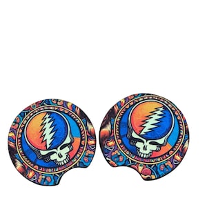 May include: Two colorful round car coasters with a Grateful Dead Steal Your Face skull design. The coasters are made of a durable material and feature a vibrant orange, blue, and yellow color scheme.