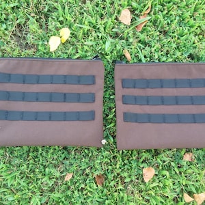 May include: Two brown zippered pouches with black webbing straps. The pouches are made of a durable fabric and have a simple design.