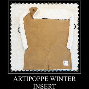 May include: A brown fleece insert for a baby carrier. The insert has a white sherpa lining and a zipper closure. The insert is labeled "Artipoppe Winter Insert".