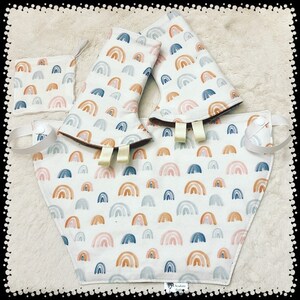 Puede incluir: Un conjunto de tres baberos para beb&eacute; con un patr&oacute;n de arco&iacute;ris. Los baberos est&aacute;n hechos de una tela suave y absorbente, perfectos para mantener la ropa del beb&eacute; limpia. Los baberos son blancos con un patr&oacute;n de arco&iacute;ris de estilo acuarela en tonos de azul, rosa y naranja.