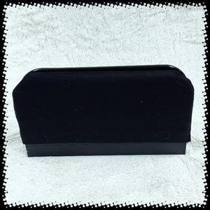 May include: A rectangular black box with a velvet top and a glossy black trim. The box is sitting on a white, textured surface. The box appears to be a jewelry box or a similar storage container.
