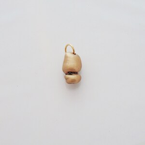 Può includere: Un ciondolo dorato con una forma irregolare unica. Il ciondolo è composto da due pezzi collegati, ognuno con una texture leggermente diversa.