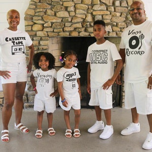May include: A family of five wearing white shirts with different music-themed designs. The shirts feature the words "Cassette Tape", "Streaming", "mp3 Audio", "Compact Disc Digital Audio", and "Vinyl Record".