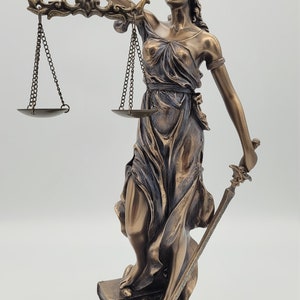 May include: Bronze statue of the blindfolded figure of Justice holding a sword and scales. The statue is standing on a book with a snake wrapped around it. The base of the statue has the inscription "Alexis R. Graves, Esq."