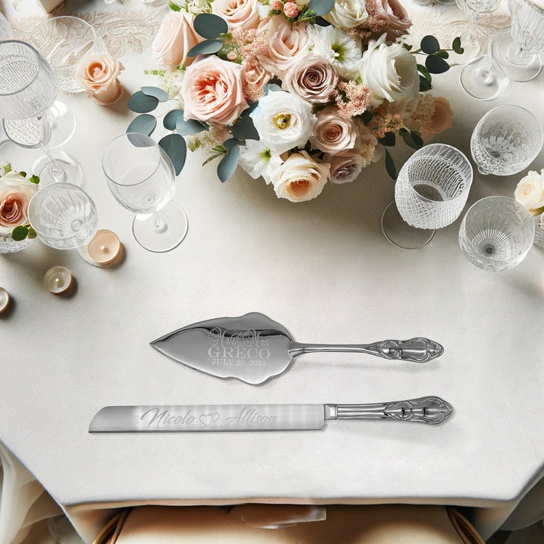 May include: A silver cake knife and server set with engraved text. The knife has the text "Nicole & Allison" and the server has the text "Mr. & Mrs. Greco July 30, 2023".