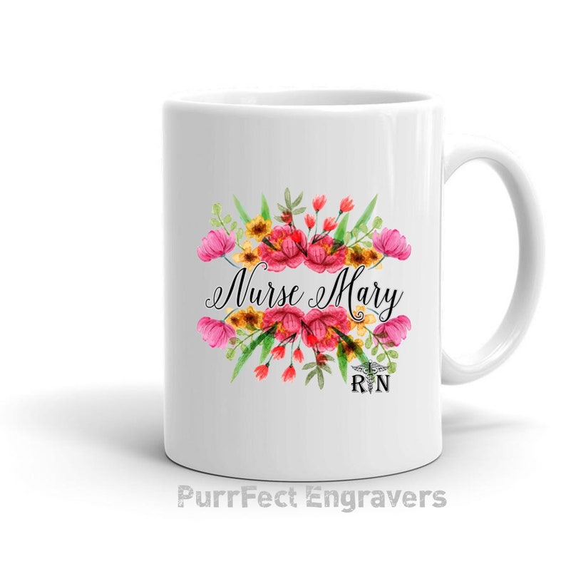 May include: White ceramic mug with a floral design and the text "Nurse Mary RN". The flowers are pink, red, yellow, and green.