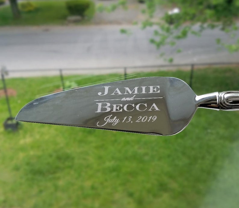 May include: Silver cake server with the text "Jamie and Becca July 13, 2019" engraved on the blade.