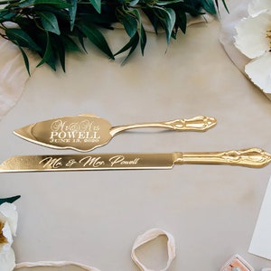 May include: Gold wedding cake knife and server set with engraved text "Mr. & Mrs. Powell June 18, 2020" and "Mr. & Mrs. Powell".