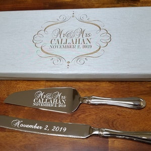 Puede incluir: Un juego de cuchillo y servidor para pastel de plata con el texto grabado "Mr & Mrs CALLAHAN NOVEMBER 2, 2019", en una caja blanca.