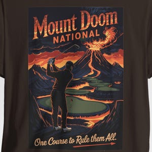May include: A brown t-shirt with a graphic of a golfer on a golf course with a volcano erupting in the background. The text "Mount Doom National" and "One Course to Rule them All" are printed on the shirt.