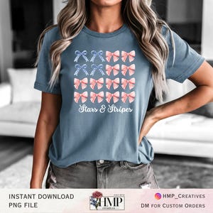 Pode incluir: Uma camiseta azul com um padrão de laços vermelhos, brancos e azuis, com o texto "Stars & Stripes" em branco. A camiseta é de estilo casual, adequada para eventos patrióticos.