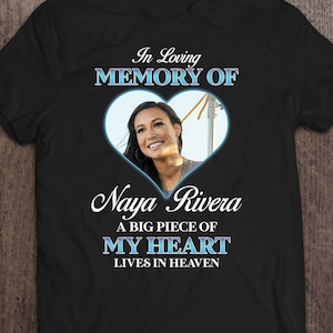 May include: Black t-shirt with a blue heart graphic and the text "In Loving Memory Of Naya Rivera A Big Piece Of My Heart Lives In Heaven".