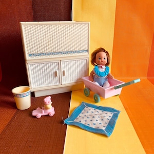 May include: A white wicker dollhouse furniture set with a doll, a pram, a toy car, and a small cup. The doll is wearing a blue and white outfit with a blue necklace. The pram is pink with blue wheels. The toy car is pink with a yellow bear in the driver's seat. The cup is yellow with a pink and blue heart design.