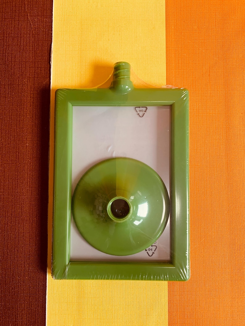 May include: A green plastic picture frame with a clear plastic cover and a green plastic funnel inside. The frame has a recycling symbol on it.