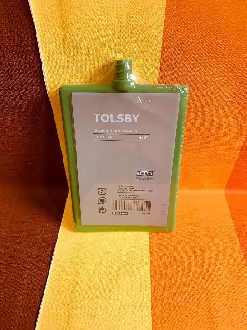 May include: A green plastic cutting board with the text "TOLSBY" and "Design Henrik Preutz" in white. The board measures 10x15 cm or 4x6 inches. The IKEA logo is in the bottom right corner.