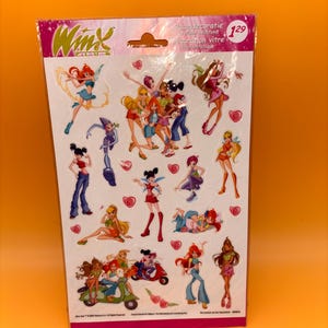 Könnte beinhalten: Ein Bogen mit Winx Club-Aufklebern mit verschiedenen Zeichentrickfiguren in farbenfrohen Outfits. Die Aufkleber befinden sich auf weißem Hintergrund und sind in einer rosa-transparenten Kunststofffolie verpackt. Die Packung hat die Nummer 129.