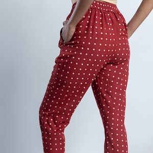 Puede incluir: Pantalón rojo con estampado de lunares blancos. El pantalón tiene un corte holgado y una longitud recortada.