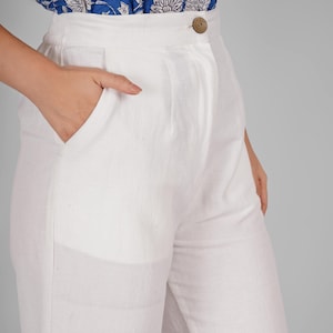 May include: White linen trousers with a single button fastening and a front pocket.