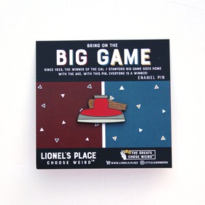 May include: A red and brown enamel pin depicting an axe with the text "Bring on the Big Game" and "Since 1933, the winner of the Cal/Stanford Big Game goes home with the axe. With this pin, everyone is a winner! Enamel Pin" on the card.