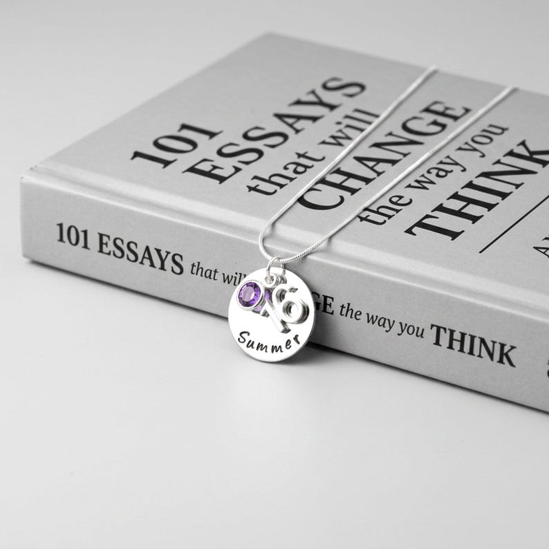 A personalised 16th birthday necklace gift laid on a closed book
