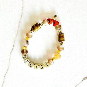 Pulsera Resist Activist para adultos y niños en tonos marrones cálidos, dorados y corazones ombré.