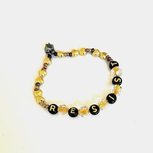 Pulsera Resist Activist para adultos y niños en negro y dorado para una declaración contundente