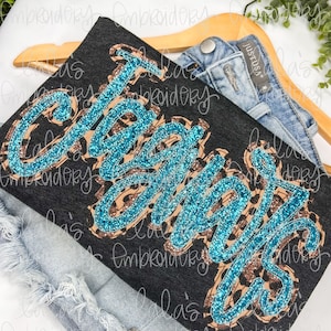 May include: A black t-shirt with the word "Cheers" in sparkly blue and brown letters on a leopard print background.