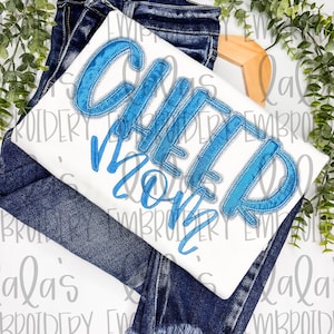 May include: White t-shirt with blue embroidered text that reads "Glitter Mom". The shirt is folded and placed on top of a pair of blue jeans.