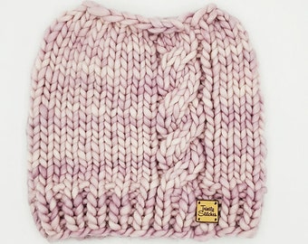 May include: A pink and white cable knit beanie with a small brown leather tag that says "Twilly Stitches".