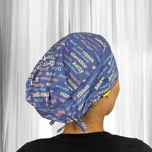 Può includere: Un cappuccio chirurgico blu navy con testo bianco, blu e giallo. Il cappuccio presenta termini medici come "elevator", "kelly" e "ribbon". Il cappuccio è legato sul retro.
