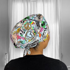 May include: A blue and white patterned surgical scrub hat with a variety of colorful graphics, including a peace sign, hearts, and the words "Wanna Dance".