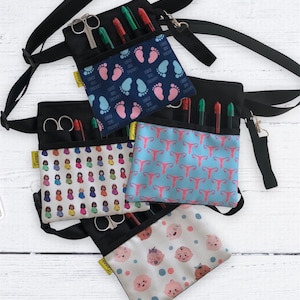 May include: Four black fabric pouches with adjustable straps, each with a different pattern. The pouches have multiple pockets and are designed to hold medical supplies. The patterns include a blue and pink footprint design, a blue and pink uterus design, a colorful doll design, and a white design with baby faces.
