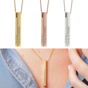 May include: Three gold bar necklaces with personalised engravings. The necklaces are shown in gold, rose gold, and silver. The engravings include names and dates.