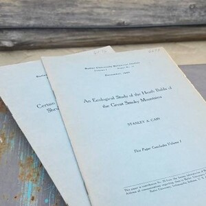 May include: A close-up of two pale blue paperbacks with the title "An Ecological Study of the Heath Bald of the Great Smoky Mountains" and the author "Stanley A. Cain". The text "This Paper Concludes Volume I" is printed at the bottom of the page.