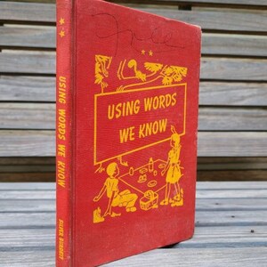 May include: A vintage red book titled "Using Words We Know" with gold lettering and illustrations. The book's cover features a stylized image of children and objects. The spine reads "Using Words We Know" and "Silver Burdett".