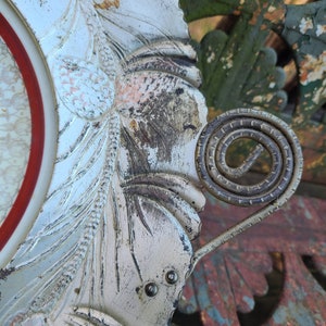 May include: A white metal tray with a decorative floral design and a spiral metal handle. The tray has a worn, aged look with some rust and discoloration.