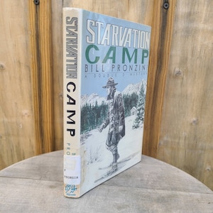 May include: A white book with the title "Starvation Camp" by Bill Pronzini. The book cover features a man in a dark coat and hat walking in a snowy landscape.