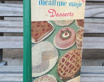 May include: A vintage cookbook titled "Margaret Mitchell's Mealtime Magic Desserts" with a green spine and a cover featuring photos of various desserts, including a pineapple upside-down cake, a strawberry gelatin mold, a coconut cake, a strawberry pie, and a plate of cookies. The text on the cover reads "over 200 tried and true recipes."