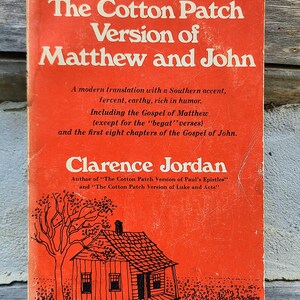 May include: The cover of a book titled "The Cotton Patch Version of Matthew and John" by Clarence Jordan. The cover is orange and features a black and white illustration of a small house with a tree in front of it.
