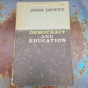 May include: A vintage paperback book with a brown cover and yellow text. The title is "Democracy and Education" by John Dewey. The book is published by Macmillan Paperbacks.