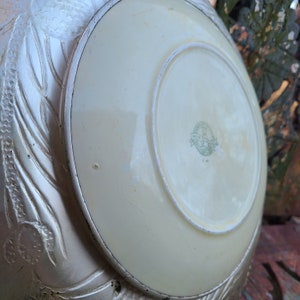 May include: A white ceramic plate with a silver rim and a green embossed logo that reads "Made in England" on the bottom.