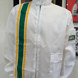 May include: A white zip-up jacket featuring a vertical green stripe flanked by two yellow stripes on the right side. The jacket has a high collar with two buttons, a small pocket on the left sleeve with a green patch reading KOOL, and a front pocket.