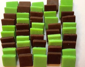 May include: A collection of small, square-shaped candies arranged in a grid pattern. The candies are alternating colors of green and brown.