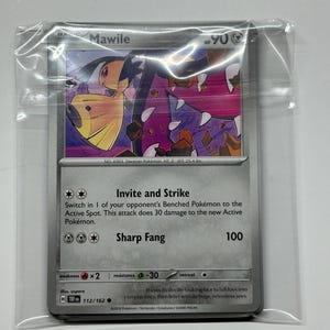 May include: A Pokémon trading card featuring Mawile, a Deceiver Pokémon. The card has a silver background with a colorful illustration of Mawile. The card is in a protective plastic sleeve.