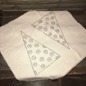 May include: A white fabric with two triangles drawn on it. The triangles are filled with a pattern of black circles.