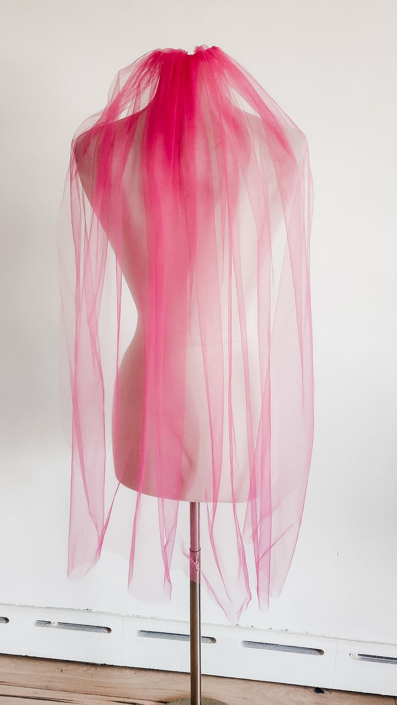 May include: A pink tulle bridal veil on a mannequin.